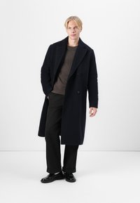 Tyylikäs sininen villasekoitekangasta pitkä takki, jossa on tuplarivinen napitus, suuret napit, kauniisti leikatut kaulukset ja hieman teksturoitu pinta.