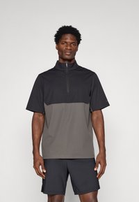 Μαύρη και γκρίζα μπλούζα με κοντό μανίκι και φερμουάρ, κατασκευασμένη από ελαφρύ ύφασμα με λείοι υφή, διαθέτει ψηλό γιακά και σχεδίαση με αντίθετα �χρώματα.