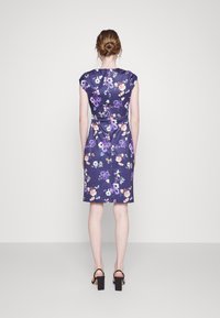 Vestido floral com fundo azul-marinho, mangas curtas, silhueta ajustada e laço na cintura. Tecido texturizado com padrões vibrantes em roxo e rosa.