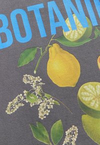 Tessuto di cotone con vivaci stampe botaniche che includono limoni gialli, foglie verdi e fiori bianchi su uno sfondo grigio scuro.