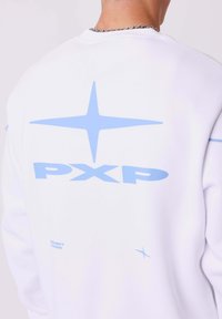 Witte sweatshirt met lichtblauwe graphics. Beschikt over een ster ontwerp en "PXP" tekst op de achterkant. Zachte stof met een relaxte pasvorm.