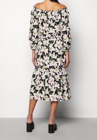 Blumenoberteil-Kleid mit schwarzem Hintergrund und weißen Lilien, elastischer Taille, gerafften Ärmeln und gestuften Saum.