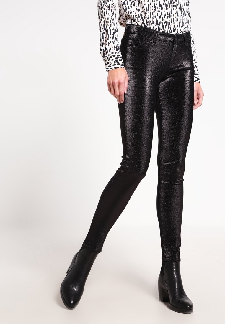 Svarta, glänsande leggings med metallstämplar och en mjuk textur, med låg midja och en tät silhuett. Matchas med svarta stövlar med klack.