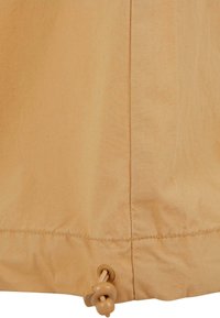 Beige tyg med en slät yta, med dragsko och tryckknappsstängning i nederkanten, samt en sömdetalj längs kanten.