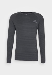 Koszulka sportowa z długimi rękawami w ciemnoszarym kolorze, wykonana z fakturowanej tkaniny z delikatnymi paseczkami. Posiada okrągły dekolt i małe logo na piersi.