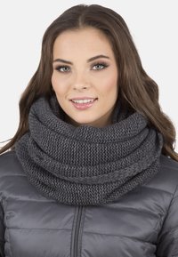 Écharpe gris tricotée avec un col en cowl et une texture de fil épais, drapée en plis lâches, associée à une veste grise rembourrée.