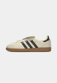 Witte leren voetbalschoenen met drie zwarte strepen, rubberen gum zool en een gevoerde tong. Kenmerkt de "Samba" branding aan de zijkant.