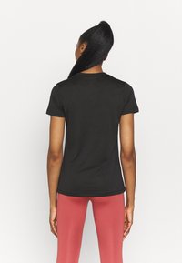 Camiseta negra de manga corta, tela ligera, diseño ajustado, cuello redondo, textura suave, mostrada desde atrás.