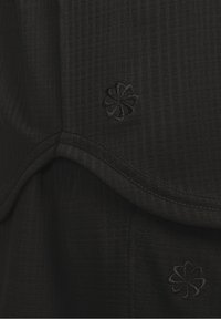 Czarna tkanina z teksturowanym wzorem w kratę. Posiada zaokrąglony brzeg z subtelnym haftowanym wzorem kwiatowym w dopasowanej czarnej nitce.