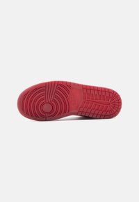 Κόκκινη σόλα παπουτσιού από καουτσούκ με κυκλικά και γραμμικά σχέδια πέλματος, διαθέτοντας λογότυπο ανάγλυφο στο κέντρο και αντίθετη πλευρική υφή.