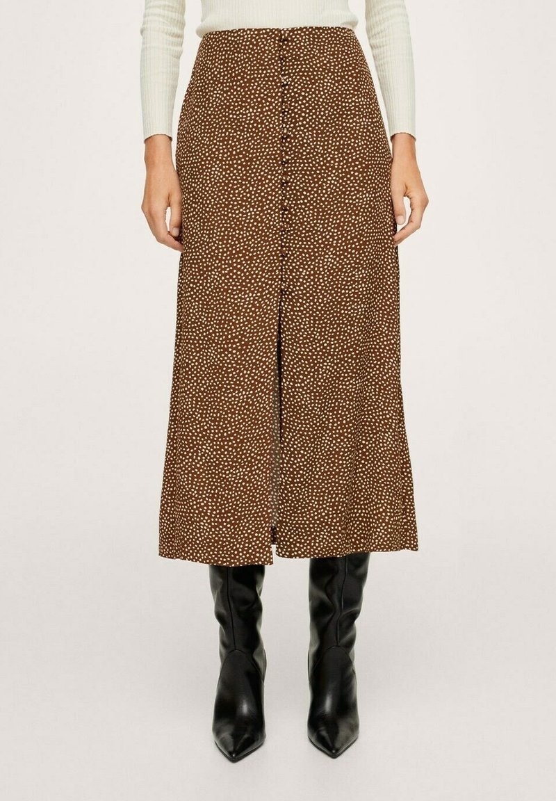Falda midi marrón con lunares blancos, botones en la parte frontal y una abertura; combinada con botas negras de caña alta y punta. Textura de tela suave.