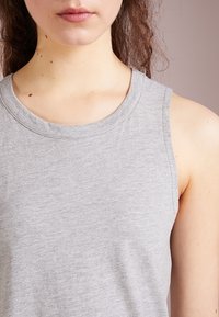 Top gris sans manches en coton doux, avec un col rond et une texture lisse. Aucune motif ou accent visible.