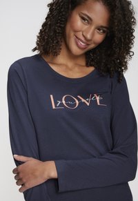 Navy blue long-sleeve top made of soft fabric, featuring a printed design with the word "LOVE" and "yourself" in light pink.