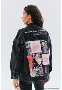 Czarna dżinsowa kurtka z kolorowym kolażem graficznym na plecach, zawierająca tekst i obrazy z serialu "Przyjaciele", z klasycznym kołnierzem typu fold-over.
