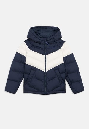 Casaco puffer azul-marinho com riscas brancas em forma de chevron, capuz e fecho com zipper. Apresenta dois bolsos frontais e textura acolchoada cosida.