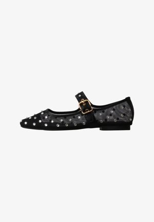 Chaussure plate Mary Jane noire avec une boucle dorée et des côtés transparents décorés de clous argentés sur fond blanc.