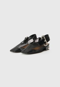 Chaussures noires à talons ouverts avec un bout pointu, en maille et cuir, présentant une boucle décorative sur la bride et un petit talon carré.