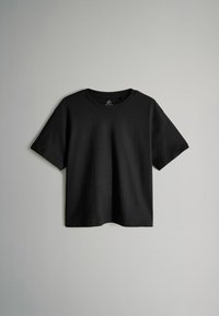 Camiseta negra de manga corta fabricada en algodón; cuenta con un ajuste relajado, cuello redondo y una textura suave y uniforme sin patrones ni acentos visibles.
