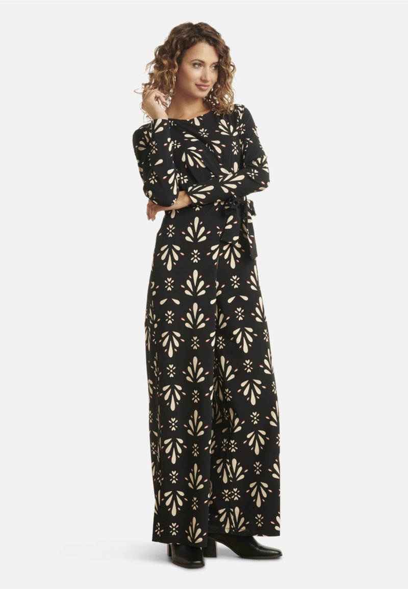 Black wrap dress with cream floral pattern, long sleeves, and a tie waist. Made of soft fabric, featuring wide legs and a flowing silhouette.