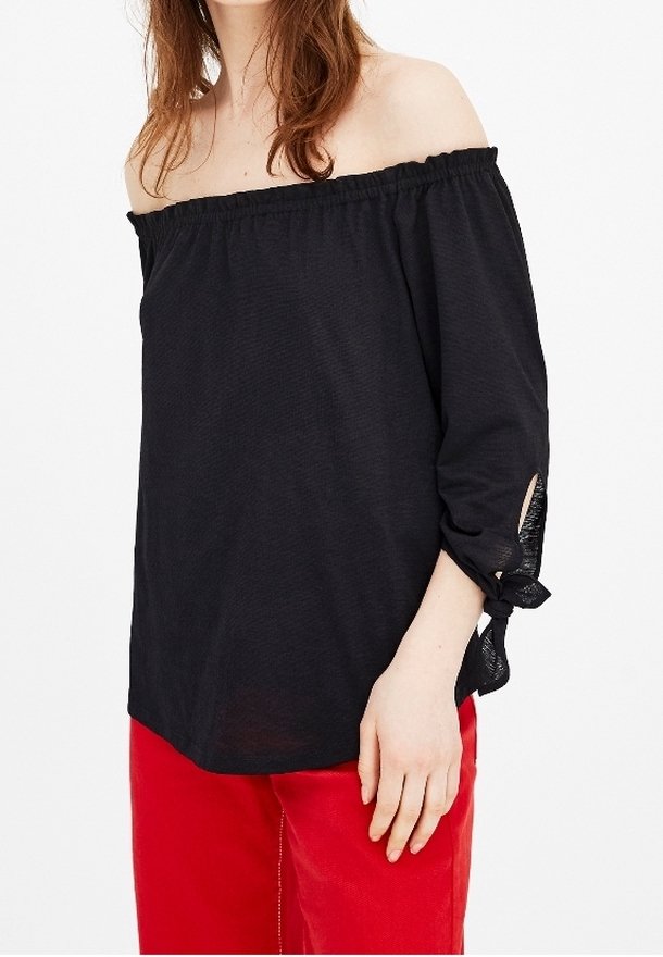Schwarze schulterfreie Bluse mit Dreiviertelärmel, die mit gebundenen Details an den Bündchen und einem leichten, strukturierten Stoff versehen ist.