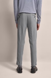 Hellgraue, strukturierte Hose im Slim-Fit-Design, mit zwei Gesäßtaschen und flachem Frontschnitt, kombiniert mit dunklen Schuhen.