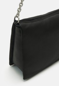Borsa a spalla in pelle nera con forma rettangolare, dotata di una tracolla con catena argentata e chiusura superiore con zip. Texture liscia e design minimalista.