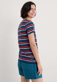 Gestreiftes kurzärmeliges Hemd in Marineblau, Rot und Türkis; kombiniert mit türkisen Shorts. Verfügt über einen runden Ausschnitt und eine lockere Passform.