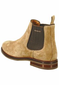 Beige Wildleder Chelsea-Stiefel mit elastischem Seiteneinsatz, abgerundeter Zehenpartie und brauner Ledersohle. Mit einem Ziehschlaufe an der Rückseite. Markenlogo sichtbar.