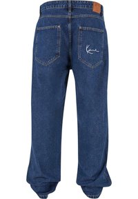 Denimjeans i en middels blå farge med en avslappet passform, med flatsydd midje, to baklommer og logo broderi på høyre lomme.