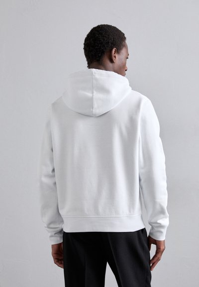 Weißer Hoodie aus weichem Material, mit einer großen, verstellbaren Kapuze und gerippten Bündchen. Einfaches, minimalistisches Design mit lockerer Passform.