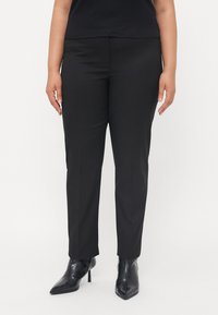 Black tailored pants with a smooth texture, slim fit, and a mid-rise waist, paired with black pointed-toe ankle boots.
