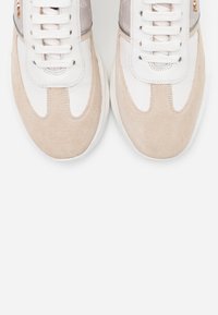 Des baskets avec un bout en daim beige, un dessus en cuir blanc et un panneau texturé gris. Comprend des lacets blancs plats et un accent de marque.