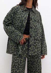 Green leopard-print jacket and matching pants, made of sturdy fabric, featuring front pockets, a collar, and button closure.