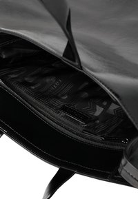 Zwarte leren totebag met ritssluiting en gevoerd met patroonstof. Heeft een zachte textuur en minimalistisch ontwerp.