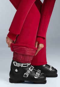 Fekete síbakancs ezüst csatokkal, piros nadrággal, melyen rugalmas szegélyek találhatók. A nadrág bokánál összehúzható a megfelelő illeszkedés érdekében.