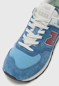 Blue suede and mesh sneaker with white laces. Features a prominent maroon "N" logo and a padded collar. Textured fabric and rubber sole.