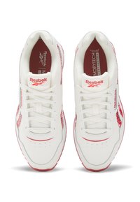 White Reebok sneakers featuring a smooth leather upper, red accents, lace-up front, and a patterned mesh panel on the sides.