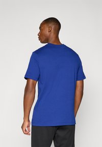 Blå bomulds t-shirt med korte ærmer, rund halsudskæring og en glat tekstur. Bagvæggen viser et enkelt design uden synlige logoer.
