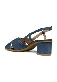 Scarpa slingback in suede blu con design a punta chiusa, dettagli intagliati e tacco quadrato. Le cinghie sono testurizzate e regolabili.