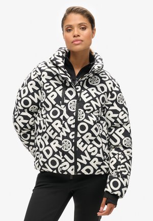 Sort og hvid pufferjakke med store tekstmønstre. Den har lynlåslukning, hætte og sidelommer med et slankt, isoleret design.