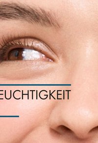 Nahaufnahme eines Auges mit glatter Haut um die hellbraune Iris, dezenten Wimpern und natürlicher Brauenstruktur, mit Textüberlagerung.