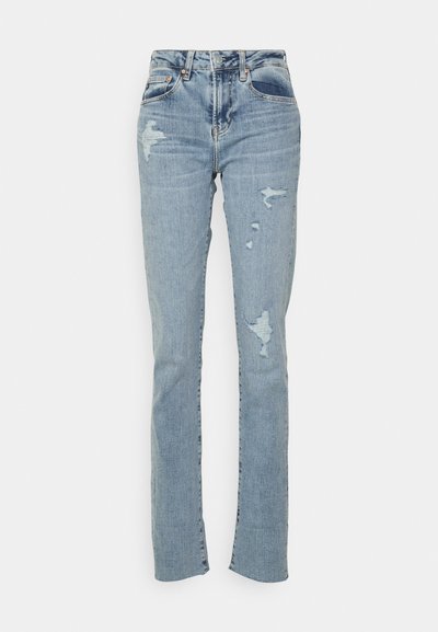 Jeans skinny bleu clair avec des patches déchirés au niveau des genoux et des cuisses, avec poches avant et passants de ceinture visibles.
