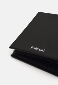 Black leather photo album with a smooth texture. The front features "Polaroid" in white text, angled at the upper corner.