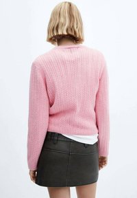Rosa Strickpullover mit strukturiertem Muster, gerippten Bündchen und Saum, kombiniert mit einem dunkelgrünen Rock. Die Rückansicht zeigt ein lässiges Design.