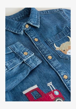 Koszula dżinsowa z klasycznym kołnierzykiem, drewnianymi guzikami i haftowanymi detalami traktora oraz krowy na przednich kieszeniach.