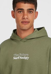 Olivengrøn hættetrøje med snor, med hvid tekst der siger "The Future Surf Society" i en blandet skrifttype. Blød stofstruktur.