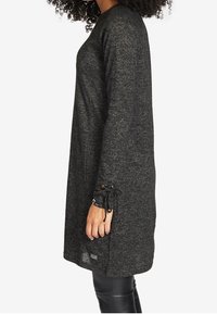 Schwarzes Langarmkleid aus Strickmaterial, mit lässiger Passform, rundem Halsauschnitt und Bindebändern an den Ärmelbündchen.