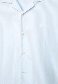 Chemise à manches courtes rayée verticalement bleu clair, avec un col classique et un logo brodé subtil. Les boutons sont de couleur crème.