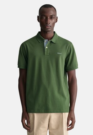 Green polo shirt with a slightly structured collar, featuring a light blue underside and a small white logo on the left chest.