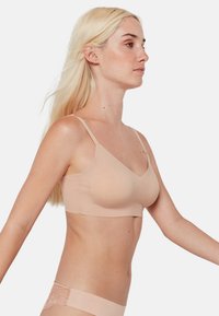 Sujetador nude sin costuras con tirantes ajustables y escote en forma de V. Tejido suave con una textura agradable y copas ligeramente acolchadas.